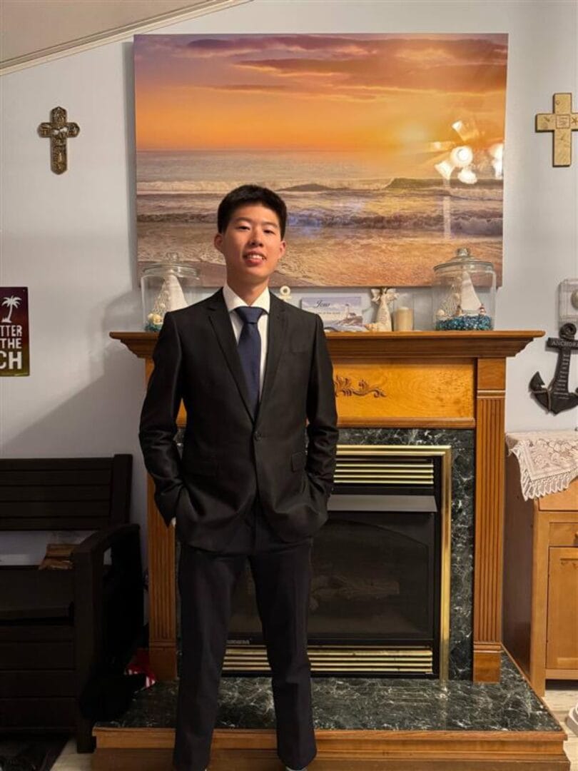 一名穿深色西裝和領帶的少年站在室內
